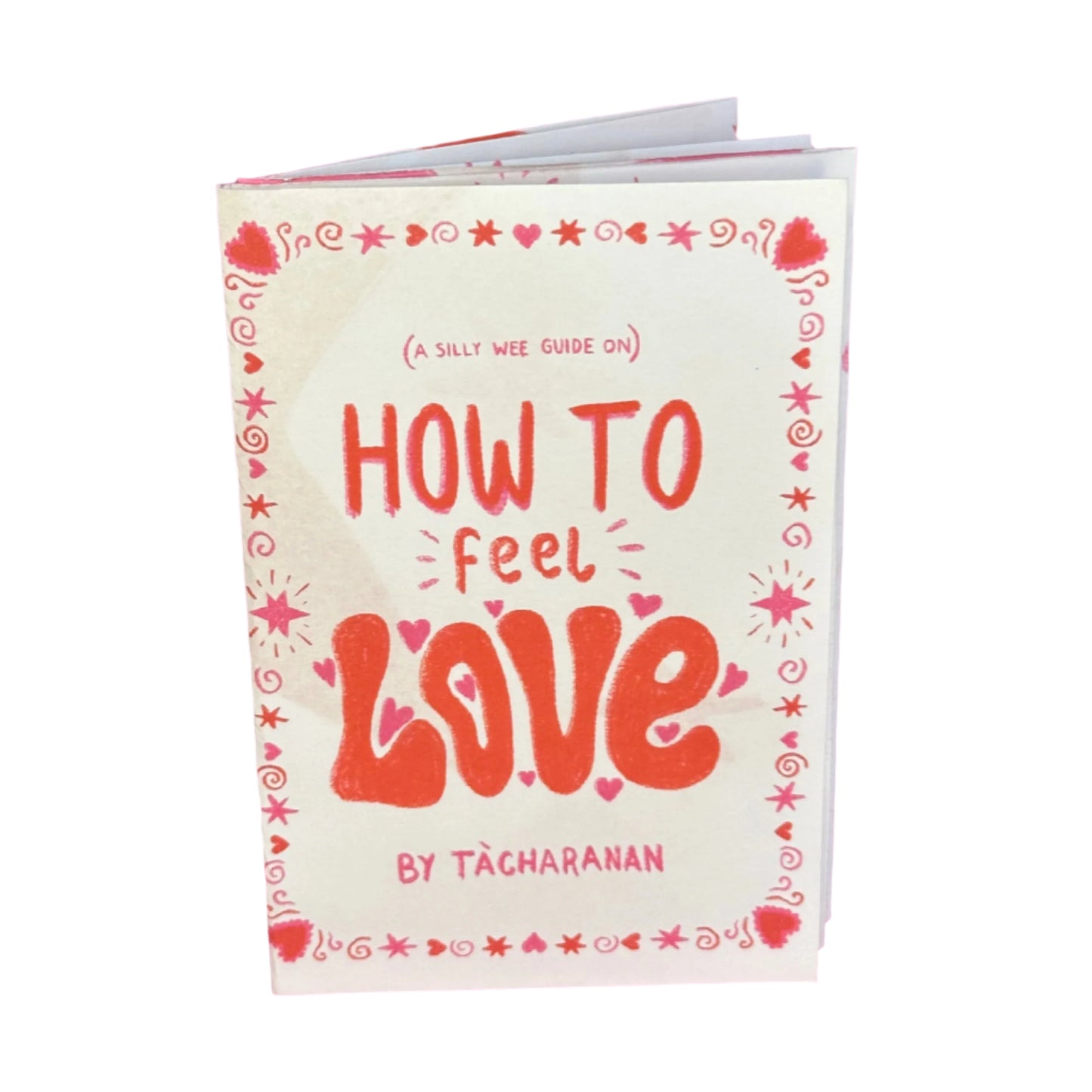 A zine titled 'HOW TO FEEL LOVE' with decorative hearts and text on the cover, held against a white background.